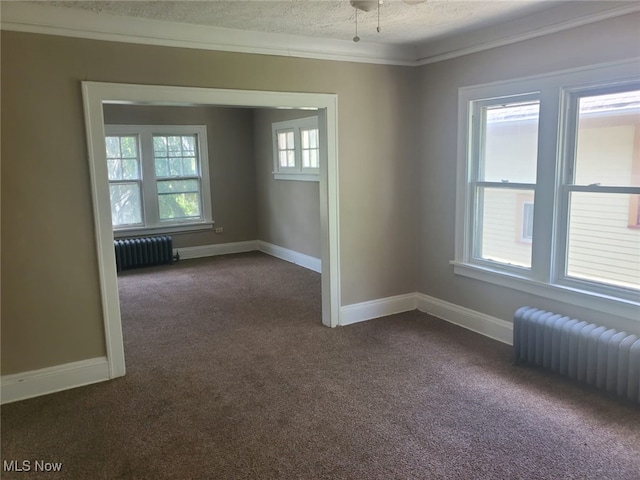 empty room featuring baseboards, radiator heating unit, dark carpet, and a textured ceiling