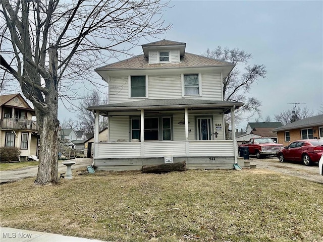 american foursquare style home featuring covered porch and a front lawn