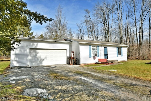 view of front of property featuring gravel driveway, an attached garage, and a front lawn