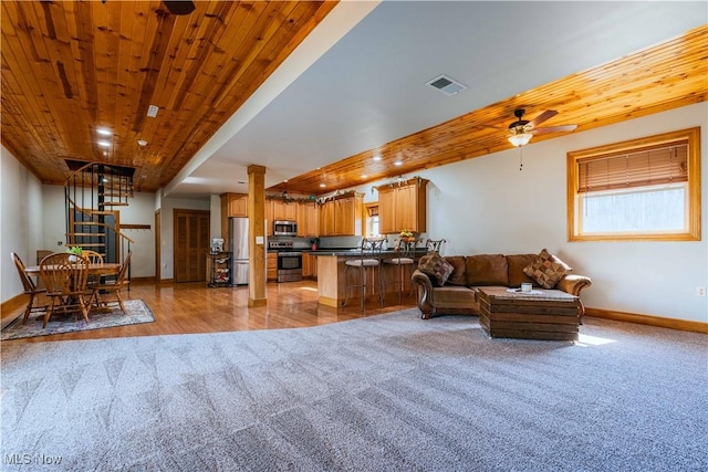 living area featuring visible vents, wood ceiling, light carpet, baseboards, and stairs