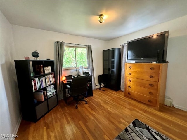 office space featuring baseboards, baseboard heating, and wood finished floors