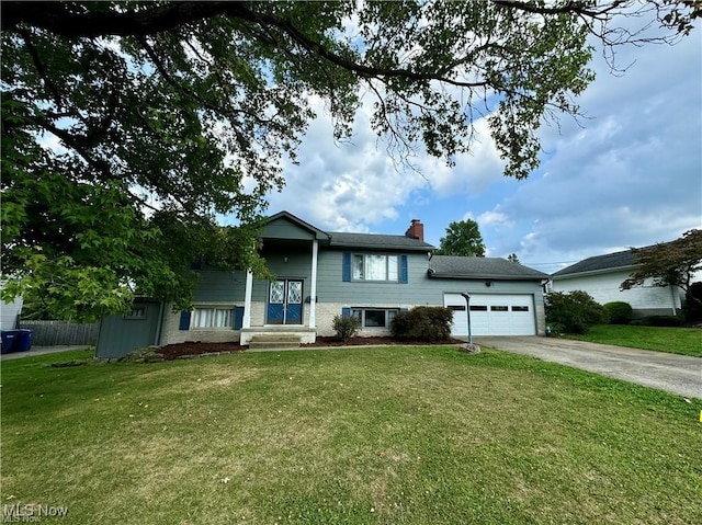 split foyer home featuring a garage, driveway, a chimney, fence, and a front lawn