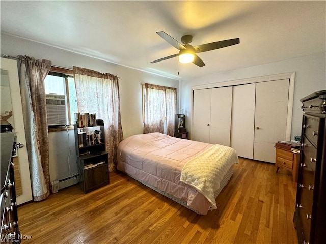 bedroom with ceiling fan, wood finished floors, baseboard heating, cooling unit, and a closet