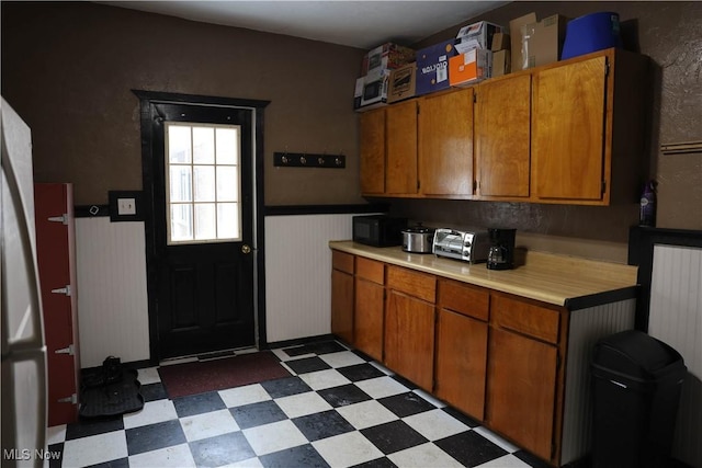 kitchen featuring light floors, black microwave, light countertops, and wainscoting