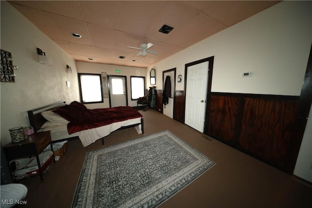 bedroom with a paneled ceiling, wainscoting, wood walls, and carpet