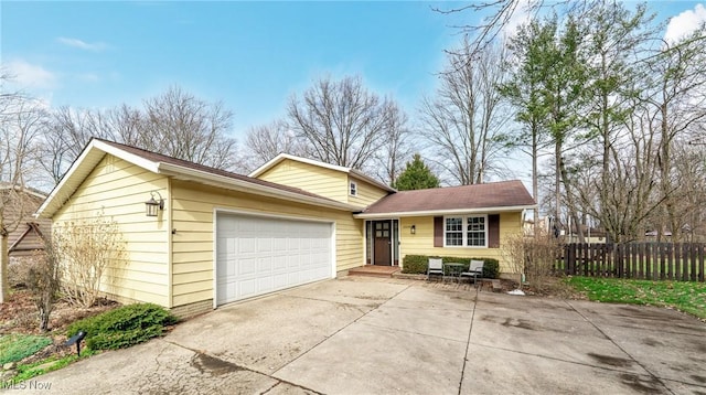 view of front of house with a garage, fence, and concrete driveway