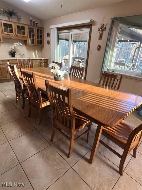 dining room with light tile patterned floors and vaulted ceiling