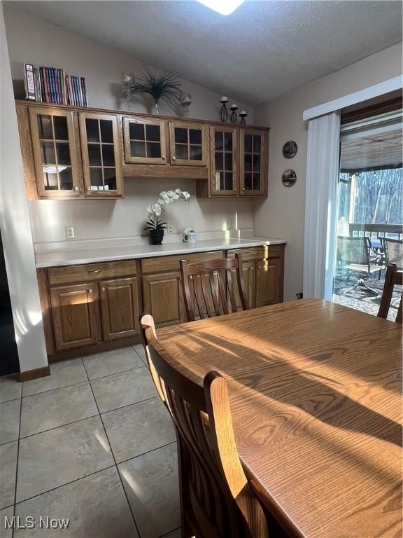 1025 Ohltown Rd, Youngstown, OH 44515 - kitchen with lofted ceiling, light countertops, glass insert cabinets, light tile patterned floors, and brown cabinetry
