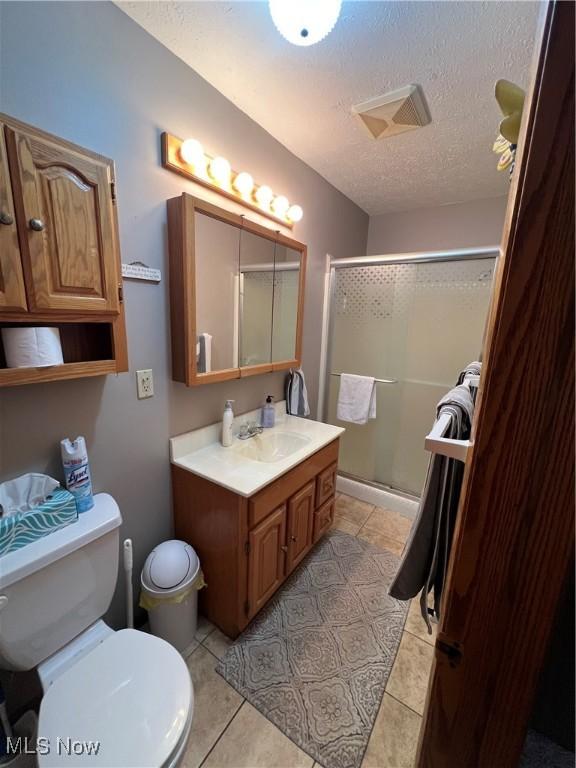 1025 Ohltown Rd, Youngstown, OH 44515 - bathroom featuring toilet, vanity, a textured ceiling, a stall shower, and tile patterned flooring