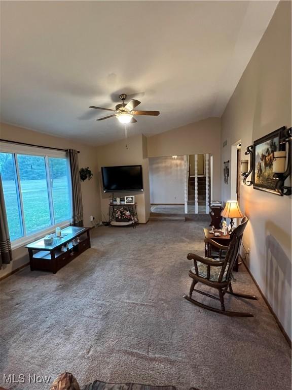 living room featuring carpet floors, baseboards, vaulted ceiling, and a ceiling fan