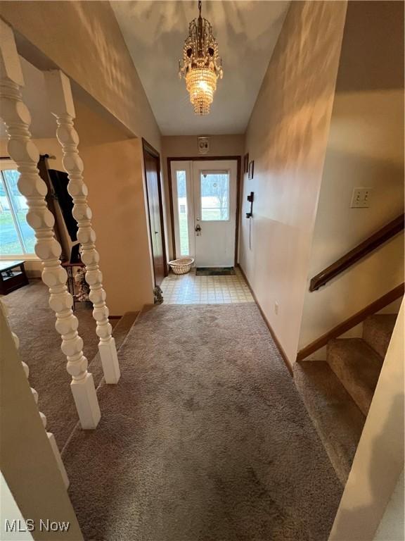 doorway with a chandelier, lofted ceiling, light carpet, baseboards, and stairs