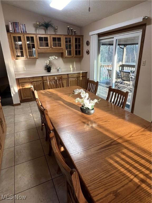 tiled dining space featuring vaulted ceiling and a textured ceiling