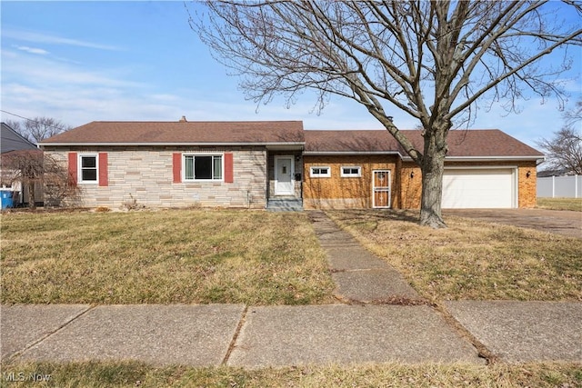 ranch-style home with driveway, stone siding, an attached garage, and a front yard