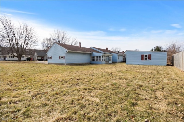 rear view of house featuring a lawn and fence