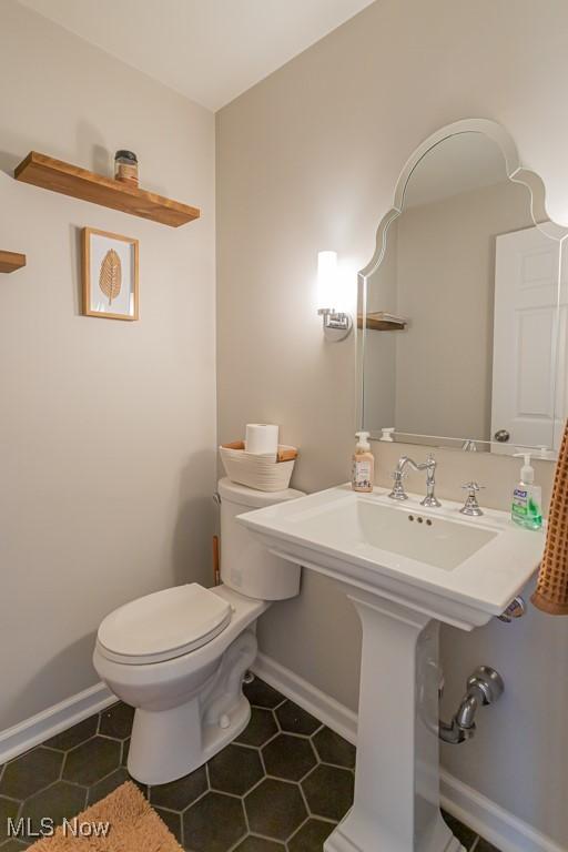 bathroom with toilet, tile patterned flooring, and baseboards