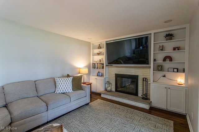 living room featuring a brick fireplace and dark wood finished floors