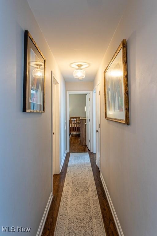 hallway with dark wood-style flooring and baseboards