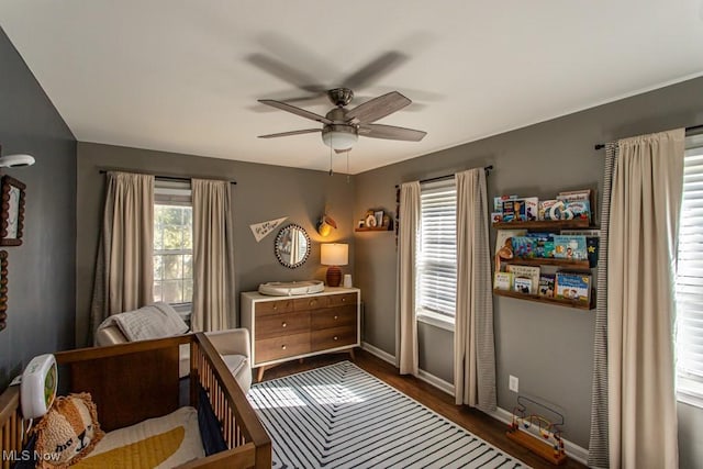 bedroom with ceiling fan, baseboards, and dark wood-type flooring