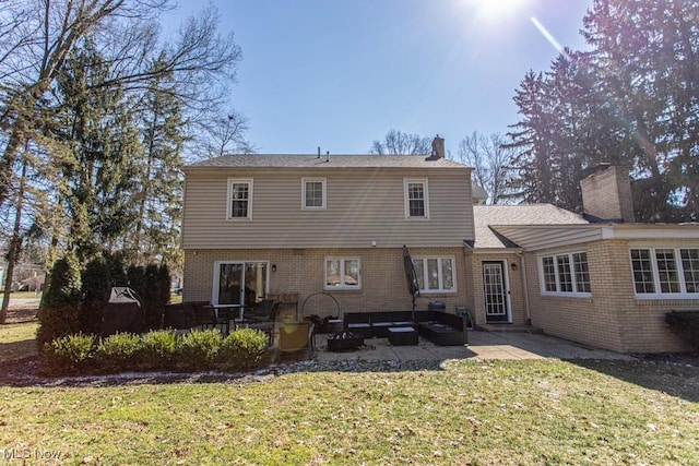 back of house with brick siding, a yard, a chimney, outdoor lounge area, and a patio area