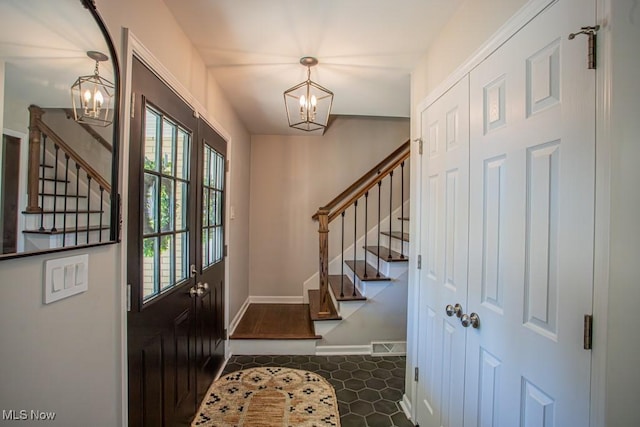 entrance foyer with baseboards, stairway, and a notable chandelier