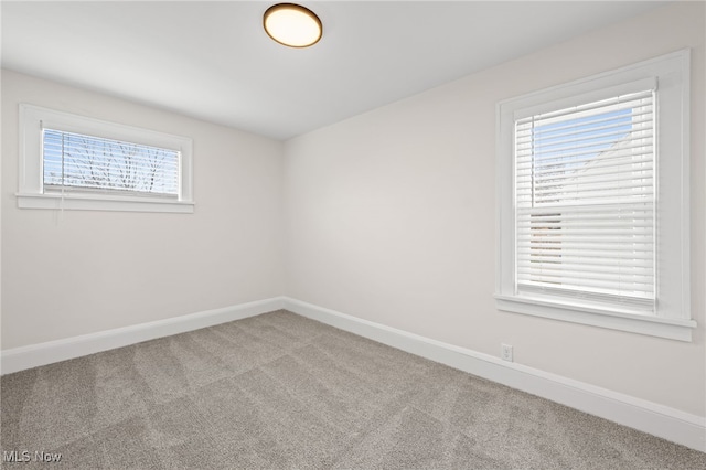 carpeted empty room featuring baseboards