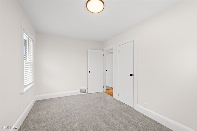 unfurnished bedroom with carpet flooring, visible vents, and baseboards