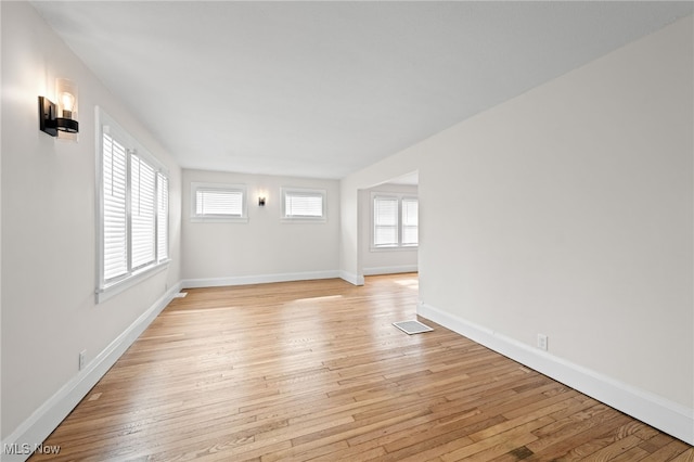 empty room featuring a healthy amount of sunlight, visible vents, baseboards, and light wood finished floors