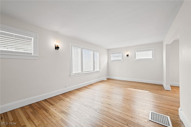 unfurnished room featuring baseboards, visible vents, and hardwood / wood-style floors