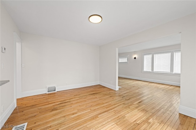 unfurnished room featuring visible vents, light wood-style flooring, and baseboards