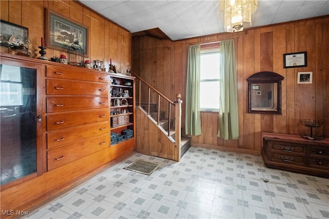 interior space with wooden walls, visible vents, baseboards, stairway, and light floors