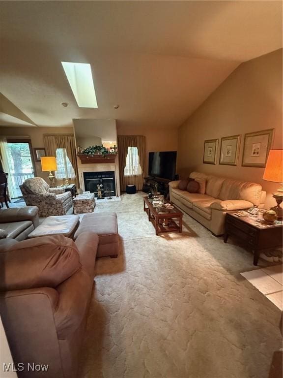 living room featuring lofted ceiling with skylight, carpet, and a glass covered fireplace