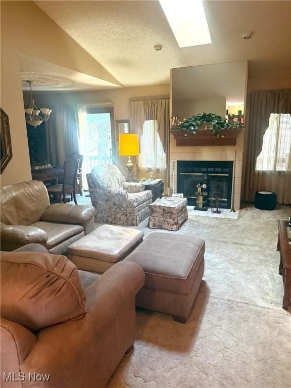 carpeted living area with lofted ceiling with skylight, a tiled fireplace, and a wealth of natural light