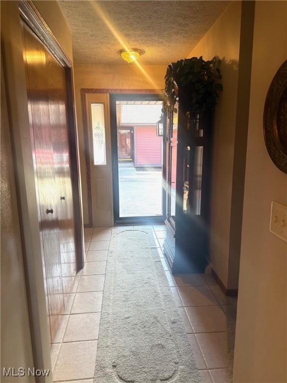 hallway with light tile patterned floors and a textured ceiling