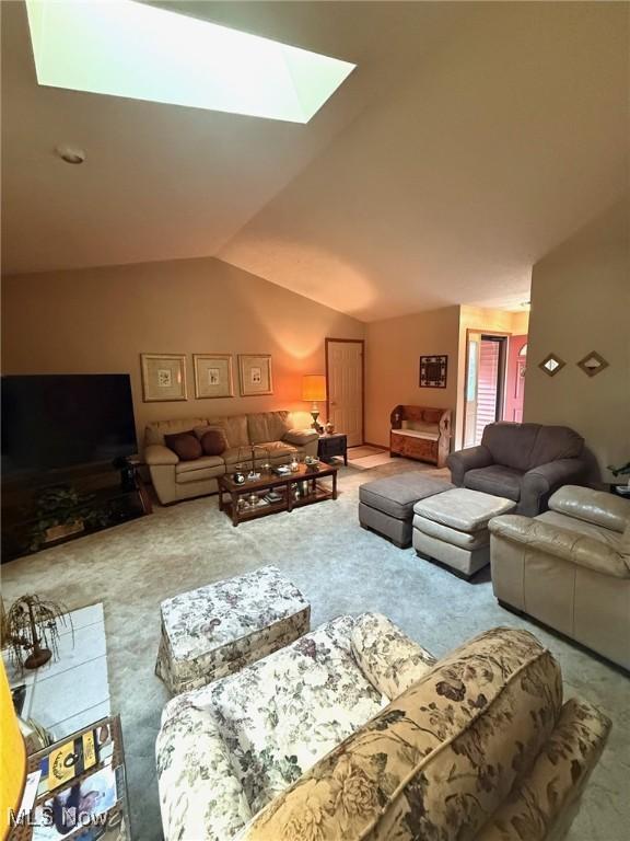 living room with lofted ceiling with skylight and carpet floors