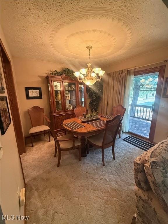 dining space featuring a chandelier, light carpet, and a textured ceiling