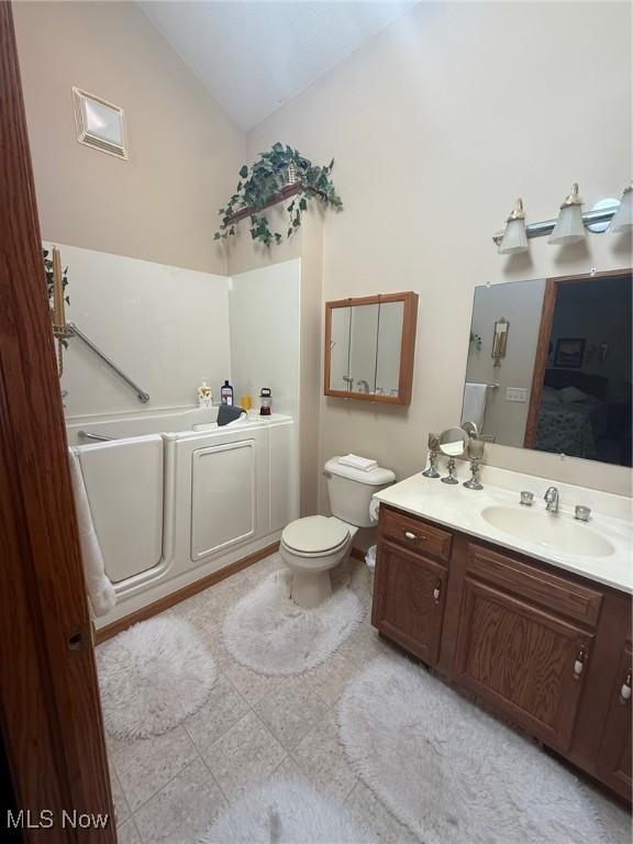 full bath with toilet, a garden tub, vaulted ceiling, and vanity