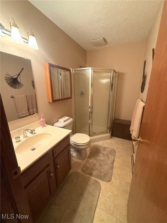 bathroom with a textured ceiling, toilet, a shower stall, and vanity