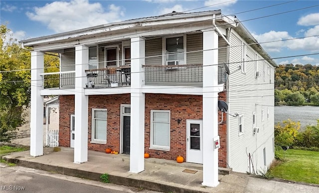 view of front of home with covered porch, brick siding, and a balcony