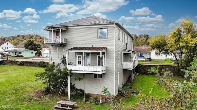 back of house with metal roof and a yard