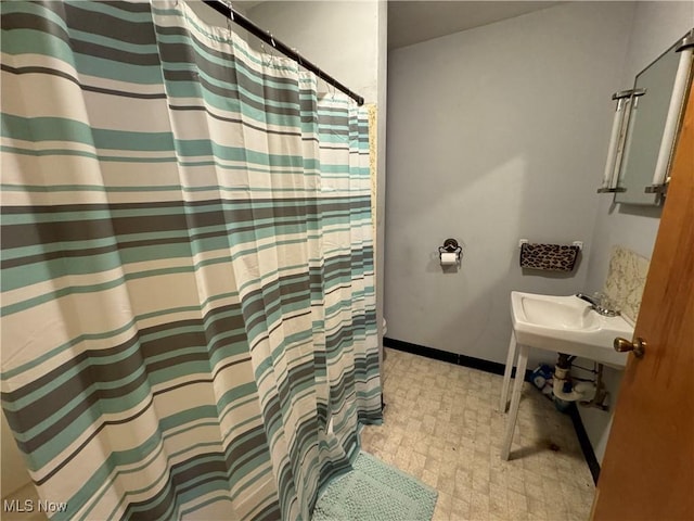 full bathroom with baseboards, a shower with shower curtain, a sink, and tile patterned floors