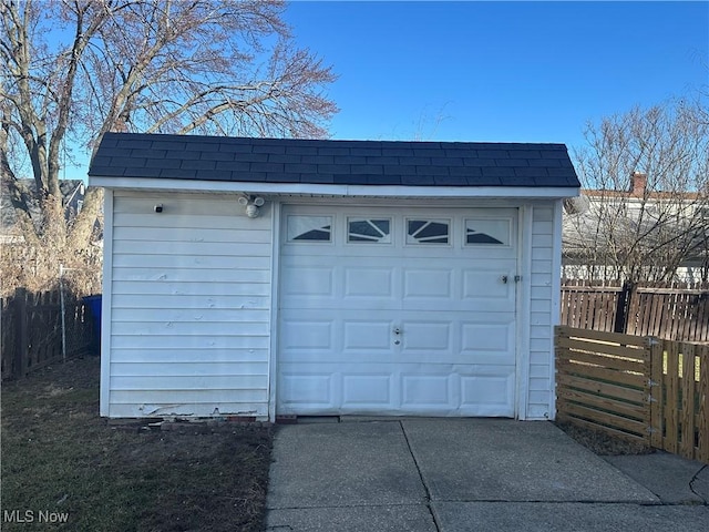 garage featuring driveway and fence