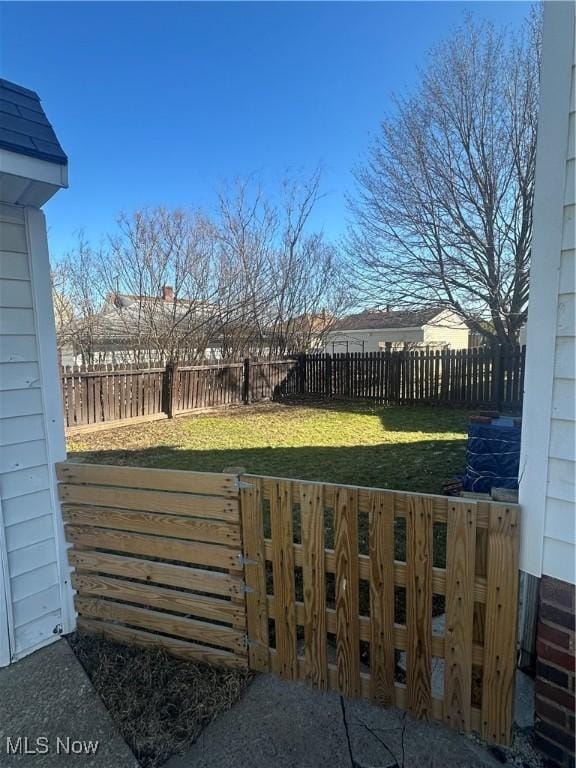 view of gate with a yard and a fenced backyard