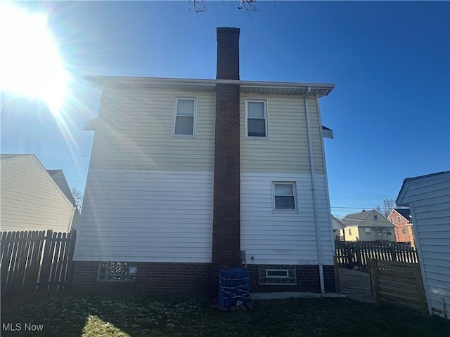 rear view of property with central AC, a chimney, and fence