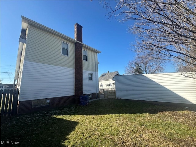 view of side of property with a yard, fence, and a chimney