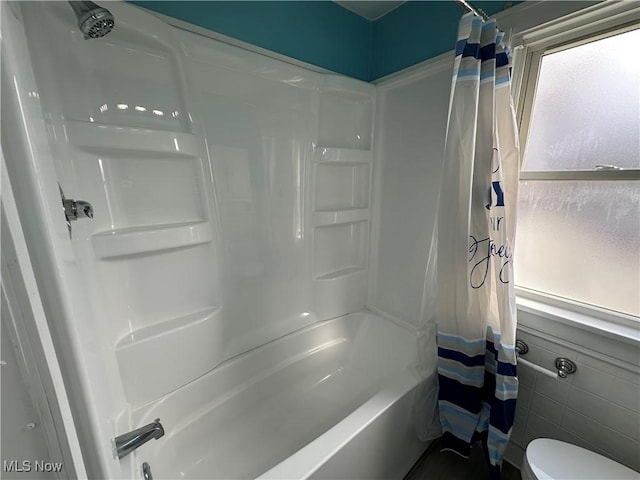 full bathroom with wainscoting, shower / tub combo with curtain, tile walls, and toilet