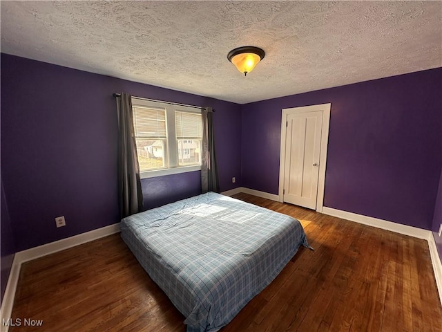 bedroom featuring a textured ceiling, baseboards, and wood finished floors