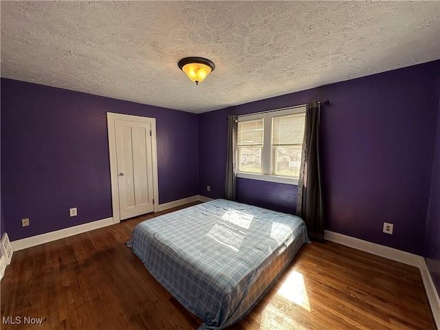 unfurnished bedroom with a closet, a textured ceiling, baseboards, and wood finished floors