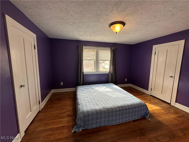 bedroom with a textured ceiling, baseboards, and wood finished floors