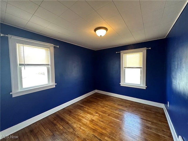 spare room featuring wood-type flooring and baseboards