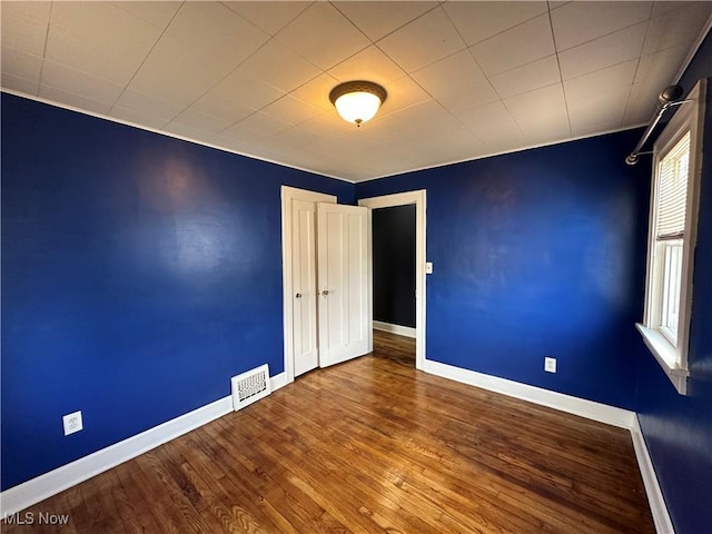 spare room featuring visible vents, baseboards, and wood finished floors